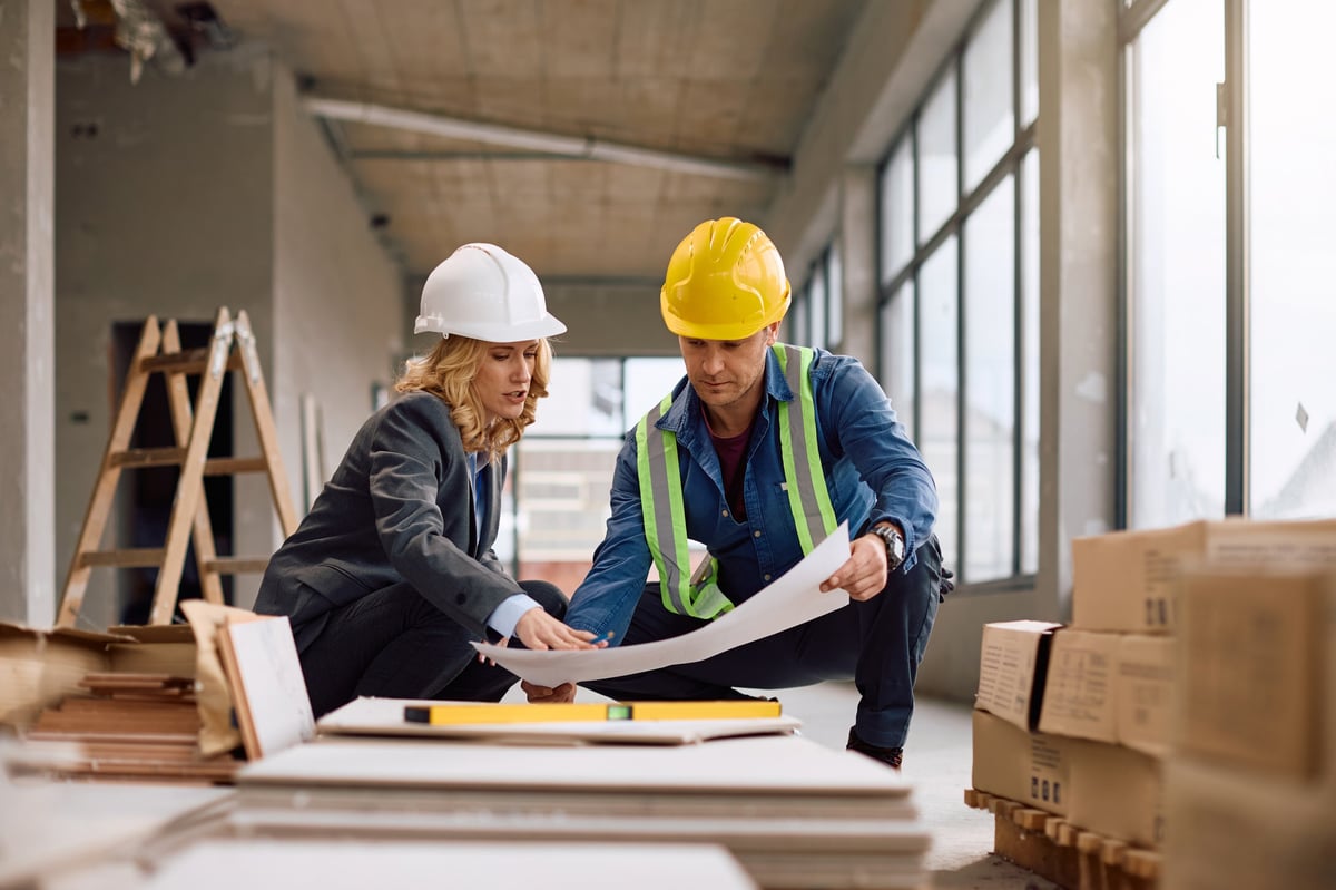 A developer and contractor reviewing building plans together on site